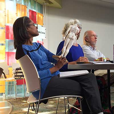 Teacher training student examing a model of the body's meridians